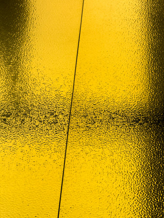 The image is a reflection of a yellow surface, possibly a piece of paper or a wall. The reflection is distorted and has a unique texture, giving it an artistic and intriguing appearanceの写真素材