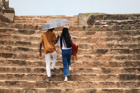 A man and a woman are walking up a set of stairs, with the woman holding an umbrellaの写真素材