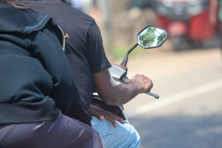 A man and a woman are riding a motorcycle together. The man is wearing a black shirt and the woman is wearing a black jacket. The woman is sitting on the back of the motorcycleの写真素材