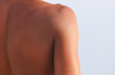 A man's back is shown with a tan color. The back is bare and has a tan colorの写真素材