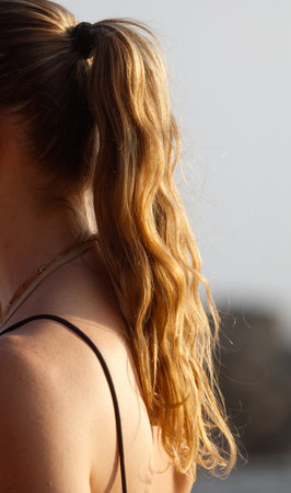 A woman with long brown hair is wearing a black tank top. The hair is styled in a ponytailの写真素材