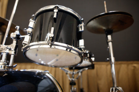 A black drum set with a white drum head. The drum set is placed on a wooden floorの写真素材