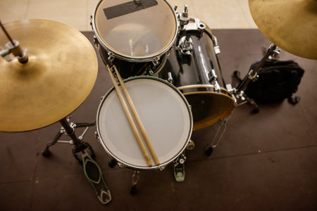 A drum set with a cymbal and a snare drum is displayed on a floor. The cymbal is positioned on the left side of the snare drum, and both drums are placed on a wooden surfaceの写真素材