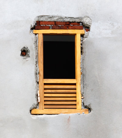 A window with a wooden frame is open, and the frame is missing a few pieces. The window is in a...