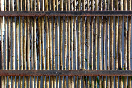 A wooden and metal fence with a rustic appearance. The fence is made of wood and metal, and it has a weathered look to it. The fence is long and narrowの写真素材