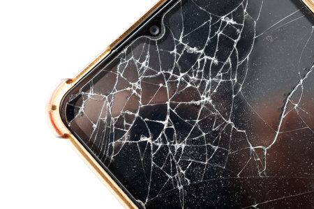 A cracked phone screen with a person's hand on it. Scene is one of destruction and damage