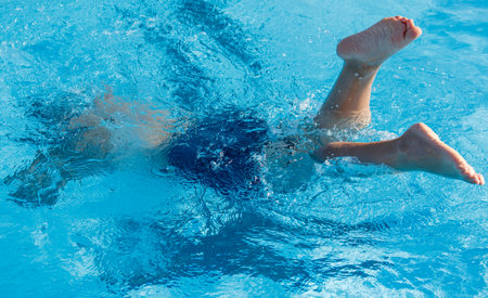 A child is swimming in a pool and is about to hit the bottom. The water is clear and calmの写真素材
