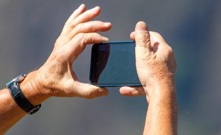 A man is taking a picture of a cell phone with his hand. Concept of nostalgia and the importance of capturing memoriesの写真素材