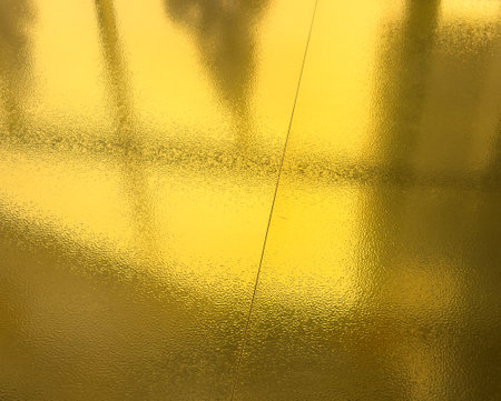 A shiny gold surface with a reflection. The reflection is blurry and the background is indistinct.の写真素材