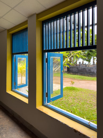 The room has two windows, one on the left and one on the right. The windows are blue and yellow, and...
