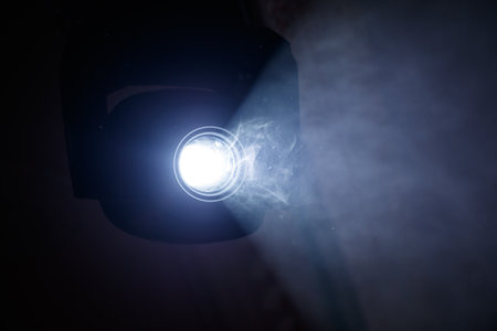 A light is shining on a dark background. The light is white and the background is blackの写真素材