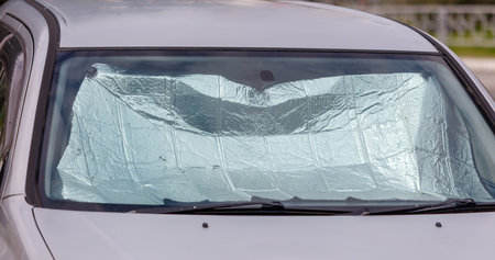 A car with a sunshade on the windshield. The sunshade is made of plastic and is covering the...