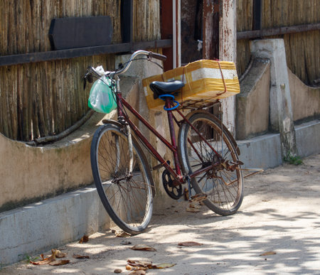 A bicycle with a plastic bag on the back. The bag is green and is tied to the handlebarsの写真素材