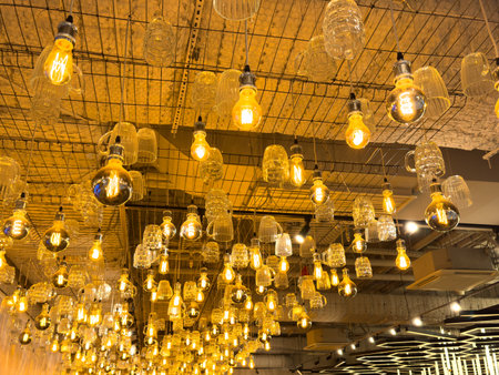 A series of lights hanging from the ceiling, some of which are lit up. The lights are arranged in a way that creates a sense of depth and movement. Scene is warm and invitingの写真素材