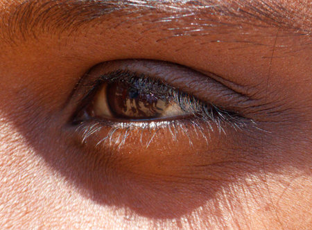 A close up of a person's eye with a shadow on the right side. The eye is brown and the shadow is darkの写真素材