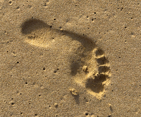 A foot print is in the sand. The sand is dry and the print is clear. The image has a calm and peaceful moodの写真素材