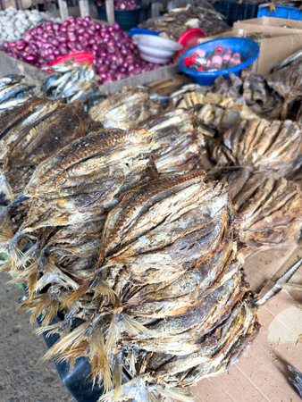 A pile of dried fish is displayed on a table. The fish are stacked on top of each other, and there are several bowls and bottles nearby. The scene gives off a rustic, market-like atmosphereの写真素材