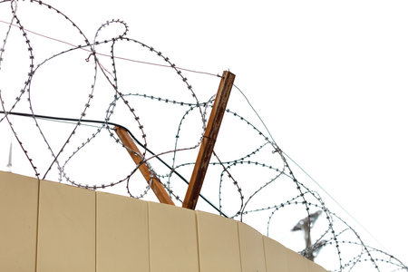 A fence with barbed wire on top of it. The fence is on a buildingの写真素材