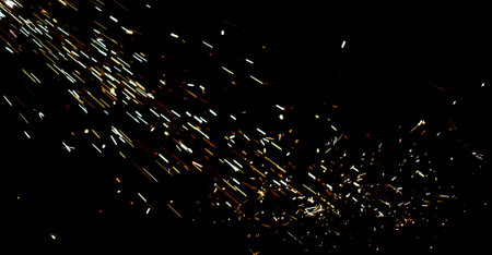 A black background with a lot of sparks and fire. The sparks are scattered all over the background and are of different sizes. Scene is intense and chaoticの写真素材
