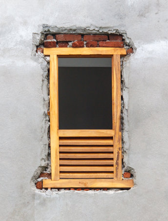 A window with a wooden frame and a brick wall. The window is open and the frame is made of wood. The brick wall is rough and unfinished, giving the window a rustic and natural feelの写真素材