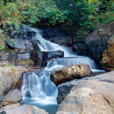 A waterfall with a stream of water flowing down it. The rocks surrounding the waterfall are large...
