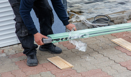 A man is working on a project, possibly installing a window. He is wearing black pants and a blue shirtの写真素材