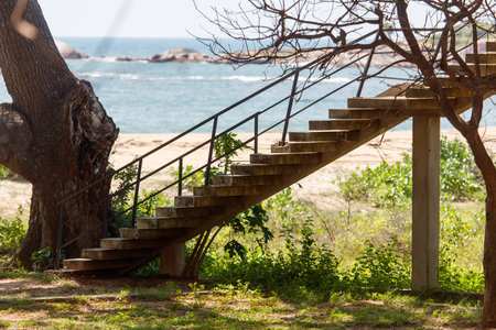 A staircase is on a beach near the ocean. The beach is empty and the water is calmの写真素材