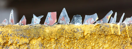 A wall covered in broken glass. The glass is scattered in a way that it looks like a mosaicの写真素材