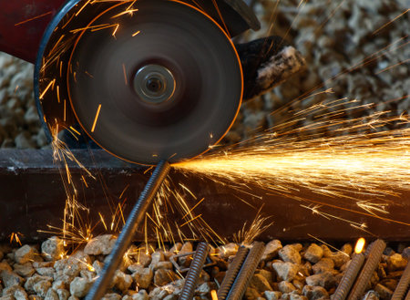 A piece of machinery is cutting through a metal bar. The sparks from the cutting process are flying everywhereの写真素材