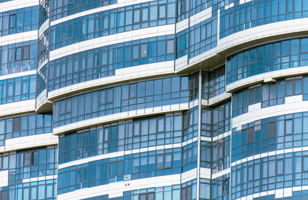A tall building with many windows and a blue tint. The windows are mostly clear, but some are tinted. The building appears to be a modern office buildingの写真素材