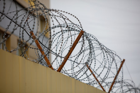A fence with barbed wire on top of it. The fence is on a building