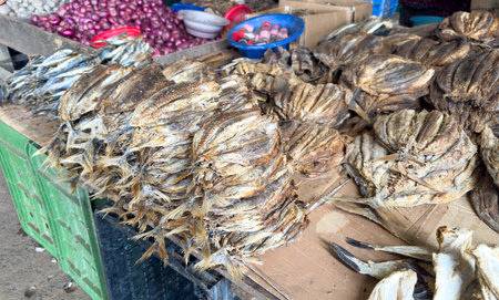 A pile of dried fish is displayed on a table. The fish are stacked on top of each other, and there are several bowls and bottles nearby. The scene gives off a rustic, market-like atmosphereの写真素材