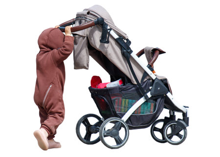 A young child is attempting to reach for a toy inside a stroller. The stroller is designed for...