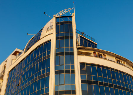 A tall building with a lot of windows and a blue sky in the background. The building is very modern and has a sleek designの写真素材