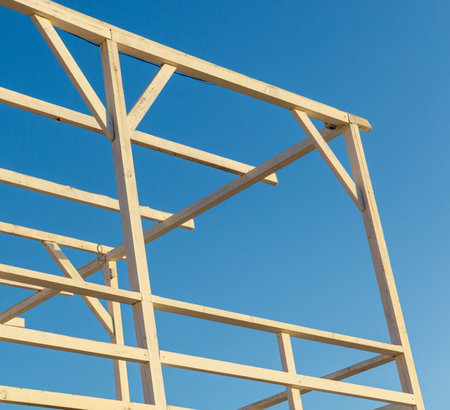 A wooden structure with a blue sky in the background. The structure is unfinished and has a lot of exposed woodの写真素材