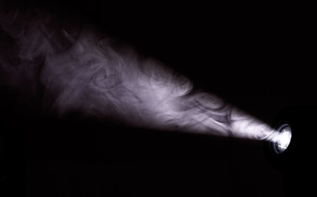 A black and white photo of a smokey, dark room with a bright light shining through the smokeの写真素材