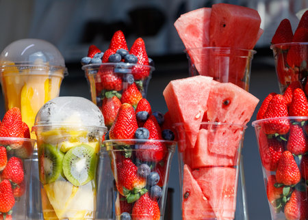 A table full of fruit in plastic cups, including watermelon, strawberries, and blueberries. The cups are arranged in a way that makes the fruit look fresh and invitingの写真素材