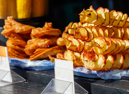 A table with a variety of food items, including chips and corn on the cob. The corn on the cob is spiralized and has a spicy flavorの写真素材