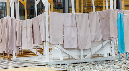 A line of clothes hanging on a clothesline. The clothes are white and blue. The clothesline is on a wooden structureの写真素材