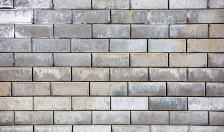 A brick wall with a gray color. The wall is made of bricks and has a rough textureの写真素材