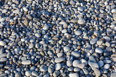 A pile of rocks with a grayish color. The rocks are scattered all over the ground. The image has a calm and peaceful moodの写真素材