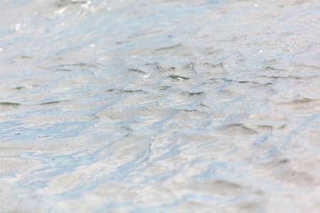 The water is calm and clear, with ripples that create a sense of tranquility. The reflection of the sky and clouds adds to the peaceful atmosphereの写真素材