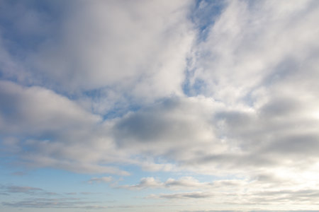 The sky is cloudy and the sun is shining through the clouds. The sky is blue and the clouds are whiteの写真素材