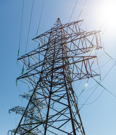 A tall power tower with many wires and a clear blue sky in the background. The tower is surrounded by a lot of wires, which are connected to the top of the tower. Concept of power and energyの写真素材