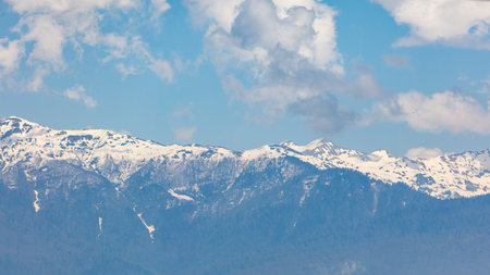 The mountains are covered in snow and the sky is blue. The mountains are very tall and the snow is very whiteの写真素材