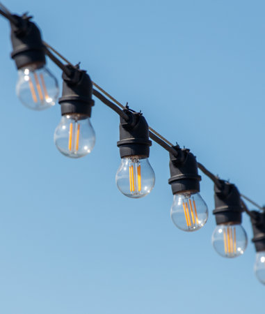 A string of lights with bulbs that are clear and yellow. The lights are hanging from a wire and are...