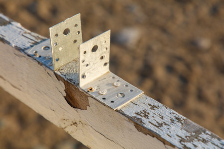 A wooden post with a white bracket on it. The bracket is attached to the post with screws