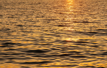 The water is calm and the sun is setting. The water is a deep blue colorの写真素材