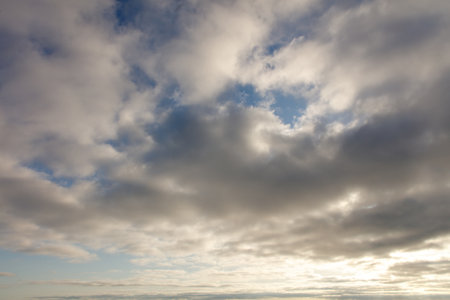 The sky is cloudy and the sun is shining through the clouds. The sky is blue and the clouds are whiteの写真素材
