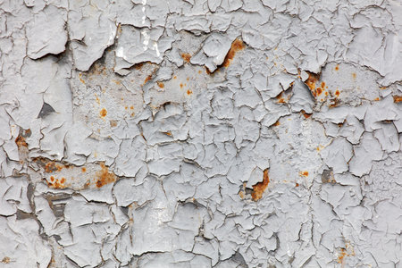The wall is covered in peeling paint and has a rustic, aged appearance. The texture of the wall is rough and uneven, with many small cracks and holes. Scene is one of decay and neglectの写真素材